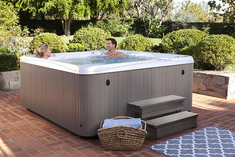 couple relax in their hot tub in the back yard