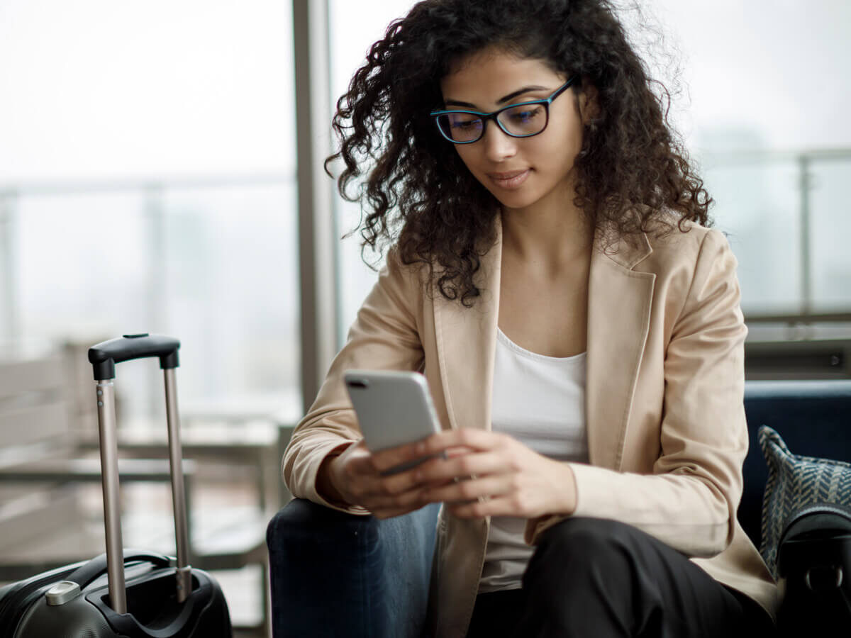 An active woman enjoying her Hot Spring Spa App on her phone during travel.