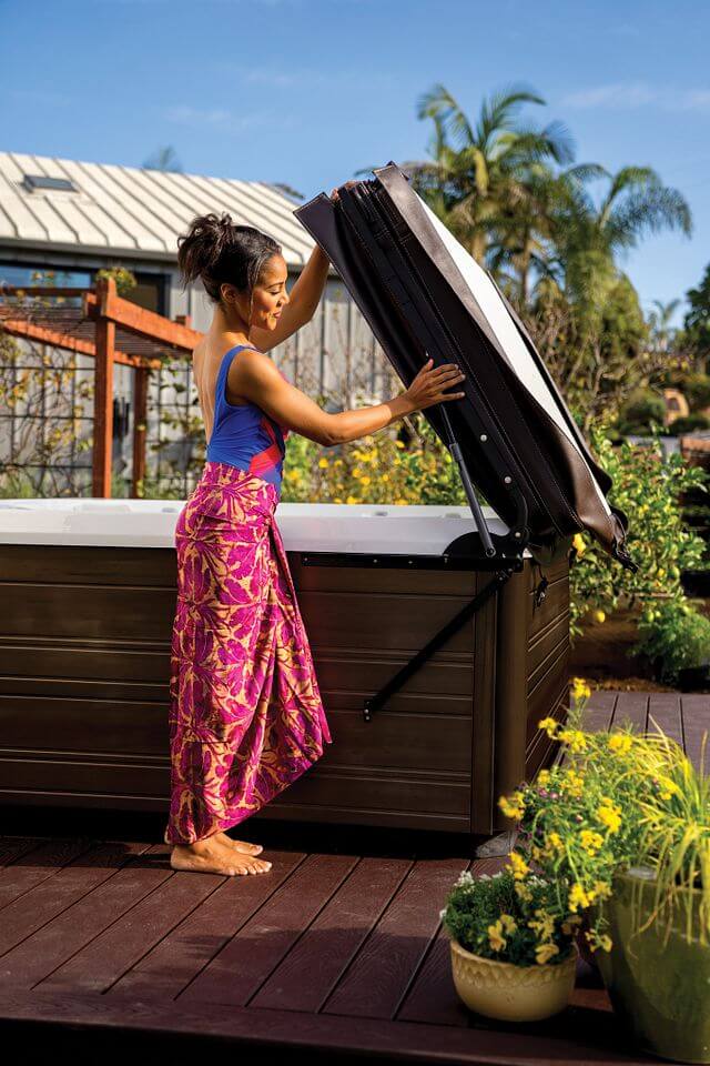 A woman lifting the Weather Pro™ Cover of a Flair® hot tub from Hot Spring Spas.