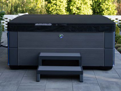 Hot Spring Spa's Aria hot tub is shown in charcoal color with a black Weather Pro™ Cover.
