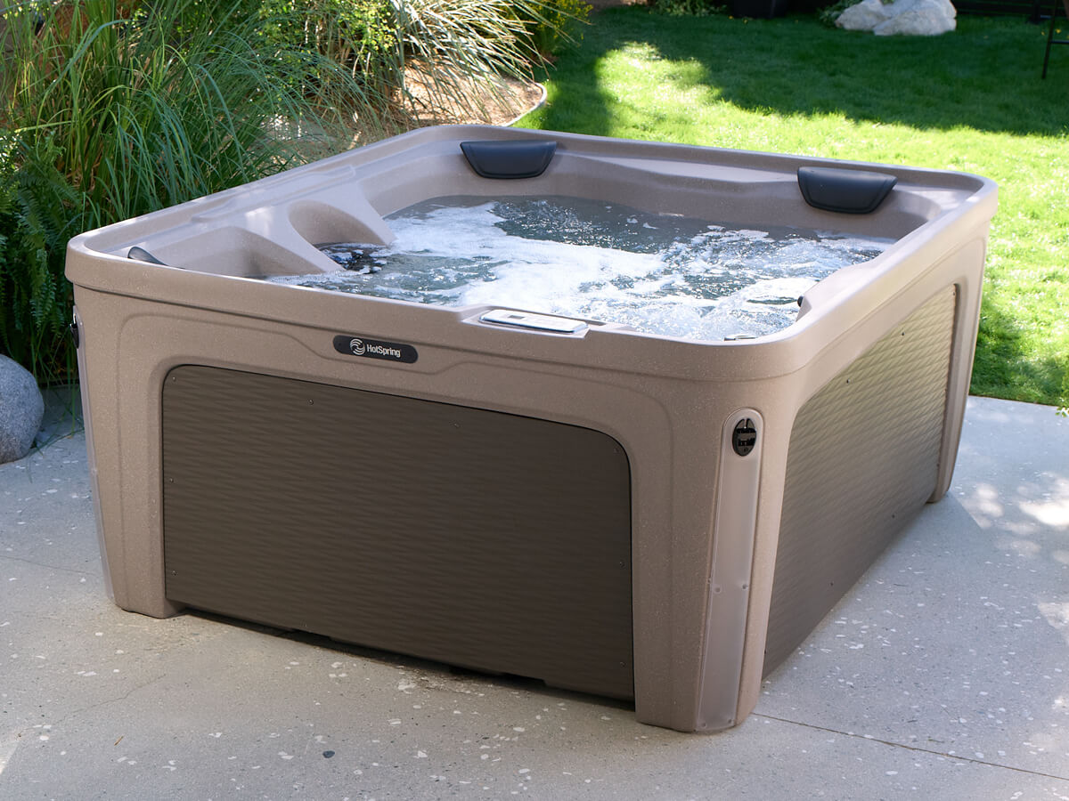 A plug-and-play hot tub with bubbling water sitting on an outdoor concrete patio